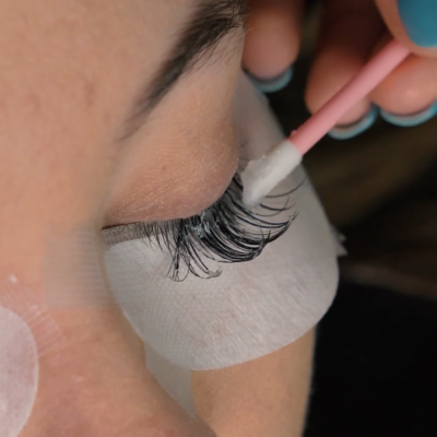 Close-up of eyelash extension removal with cream remover and micro brush