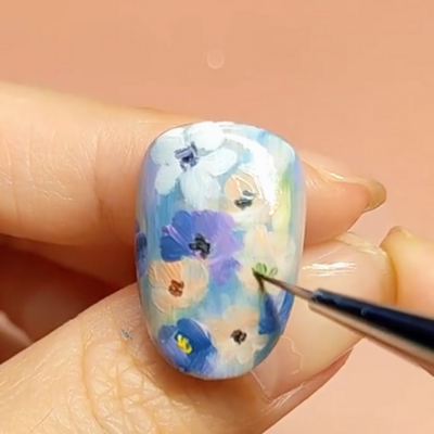 Detailed floral nail art being applied to a fingernail with a fine brush.