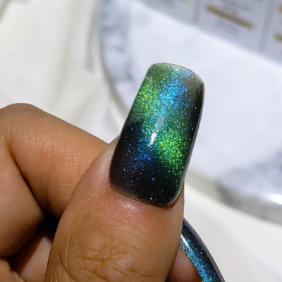 Close-up of a hand showing green and blue glitter gradient nail art